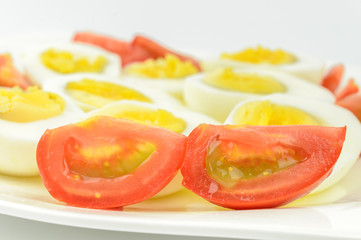 tomatoes and boiled eggs on a white plate
