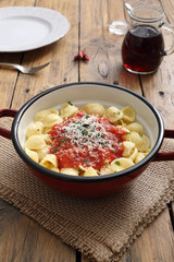 pasta italiana orecchiette pomodoro e formaggio in tegame di metallo sfondo legno rustico