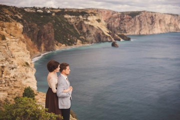 Naklejka premium Romantic and stylish caucasian couple standing on the background of spectacular sea view. Love, relationships, romance, happiness concept.