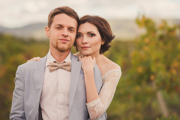 Romantic and stylish caucasian couple standing in the beautiful vineyard at sunset. Love, relationships, romance, happiness concept.