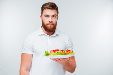 Portrait of a bearded man holing plate with fresh salad