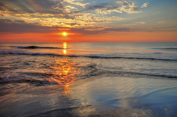 Obraz premium Beautiful sunrise over the sea with dramatic clouds on the sky