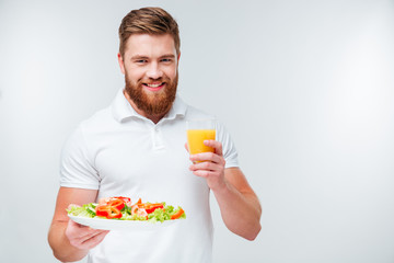 Man holding plate with vegetables and glass of orange juice