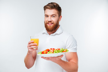 Man holding plate with vegetables and glass of orange juice