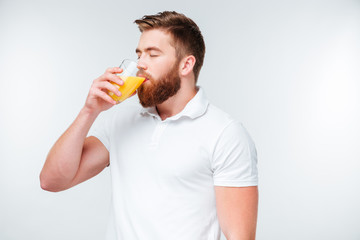 Young handsome bearded man drinking orange juice