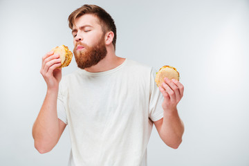 Excited bearded man enjoying eating hamburgers