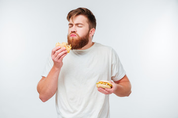 Excited bearded man enjoying eating hamburgers