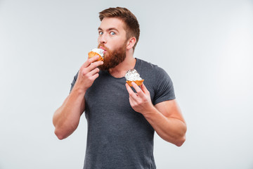 Happy bearded man biting cream cake