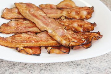 Delicious fried bacon strips on a plate
