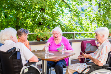 Gruppe Seniorinnen spielt auf Terrasse von Altenheim