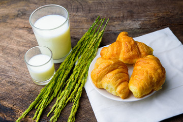 Croissant on dish with rice milk and ear of rice  on old wooden