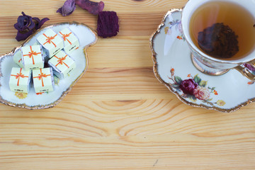 Chocolate sweets and a cup of tea on wooden background. Toned image.