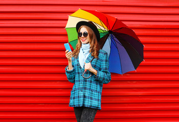 Fashion pretty young smiling woman with colorful umbrella using