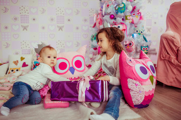 Little brother and sister play with large pink present box