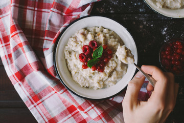 Oatmeal with berries and mint on a brown background