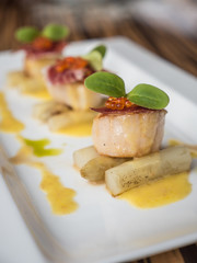 Seared scallops with salmon roe, ham and asparagus on plate