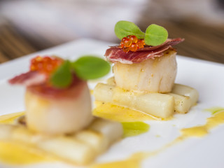 Seared scallops with salmon roe, ham and asparagus on plate