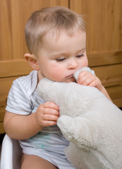 Sad two and half year boy with soft toy pig is sitting on a white plastic potty - 124887805