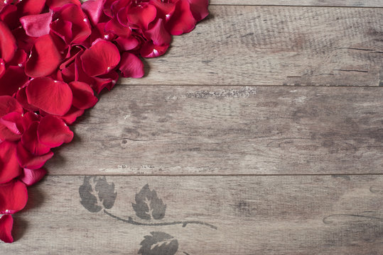 Red rose petals on the wooden background.  Border on a wooden table. Top view, copy space. Floral frame. Styled marketing photography. Wedding, gift card, valentine's day or mothers day