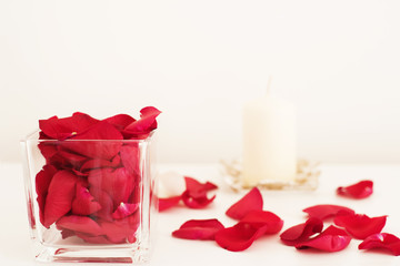 Glass vase filled with red rose petals, white aromatic vanilla candle. Aromatherapy concept. Glass vase filled with red rose petals, white aromatic vanilla candle.  Aromatherapy concept. 