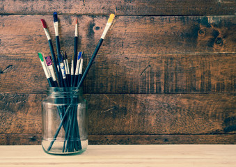 Used paint brush in jar with wooden background