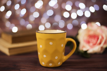 Coffee cup, tea, old books and rose on wood table in cafe with bokeh light background. Leisure lifestyle concept. Coffee on table in the night. Rustic background with beautiful 