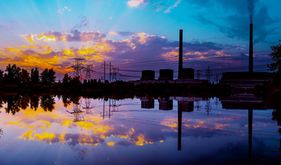 Coal power plant at sunset and reflection in water.