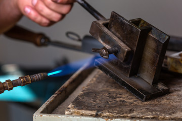 Close-up of Goldsmith using Blowtorch on Metal Mold in order to melting Metal; Goldsmith Workshop