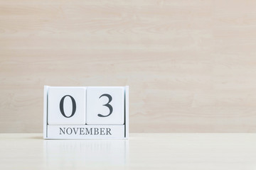 Closeup surface white wooden calendar with black 3 november word on blurred brown wood desk and wood wall textured background with copy space , selective focus at the calendar