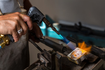 Close-up of Goldsmith hands melting Silver to liquid state in crucible with blowtorch