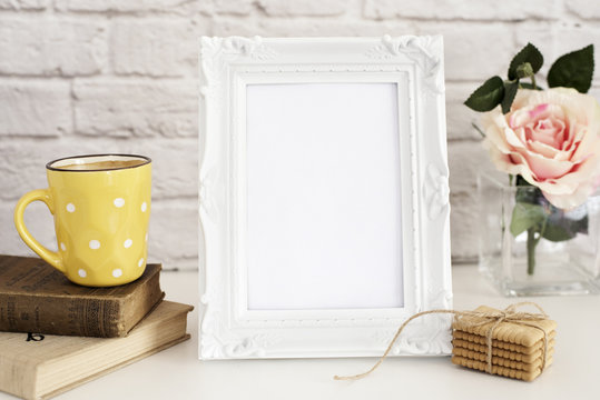 Frame Mockup. White Frame Mock Up. Yellow Cup Of Coffee With White Dots, Cappuccino, Latte, Old Books, Cookies. Vase with Flower Rose, Styled Stock Photography. Empty Frame. Leisure Lifestyle Concept.