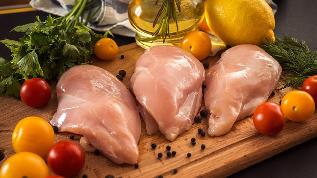 Raw chicken breast fillets and vegetable on wooden background