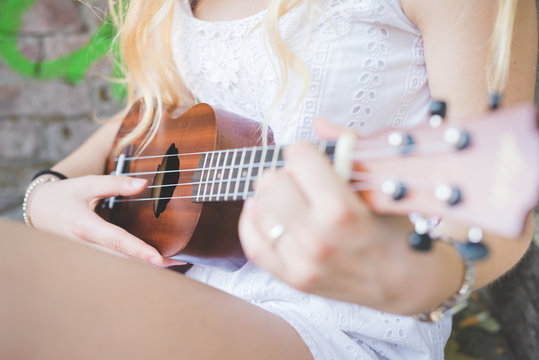 Close up hand young millennial caucasian woman playing ukulele - music, song, chord concept