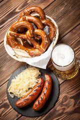 Pretzels, bratwurst and sauerkraut on wooden table