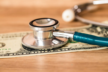 Stethoscope on Bank note one dollar money on wooden background ,Determined image for solution or key to protect and check money with out risk concept.