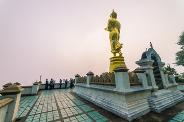 Fototapeta na wymiar Sunrise scence of Golden Buddha statue standing on a mountain Wat Phra That Khao Noi, Nan Province, Thailand
