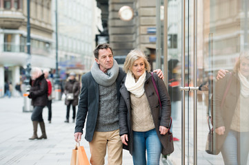 Senior couple window shopping in city centre. Winter