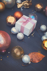 Christmas golden and silver decorations on dark wooden background with gift box, retro toned