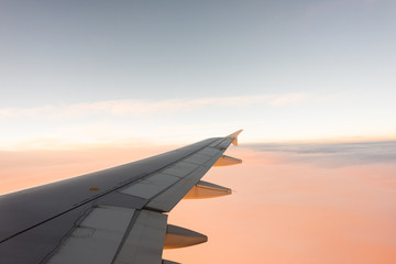 Naklejka na ściany i meble Wing of the airplane on pink sky background at sunset