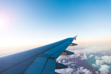 Wing of the airplane on blue, yellow and pink sky background at sunset