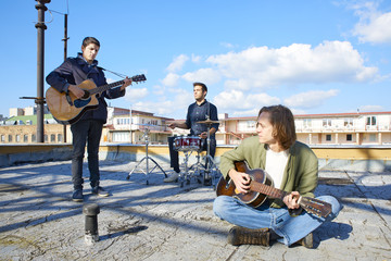 Full length shot of a pop band playing music on outdoor scene. 