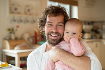 Young father holding his little daughter in his lap