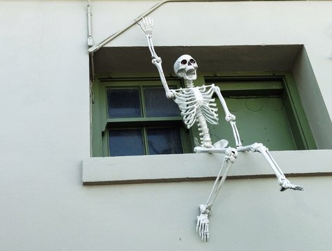 Halloween-Dekoration: Skelett sitzt winken auf Fensterbank
