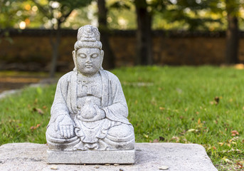 Fototapeta na wymiar A small stone buddha at a green garden in Korea