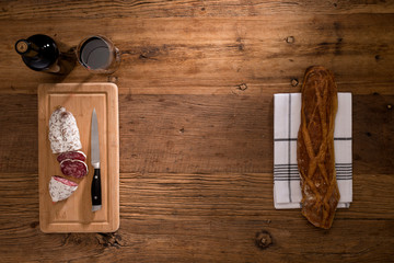flat lay above view of dry sausage delicatessen sliced meat with wine and traditional bread on wooden board