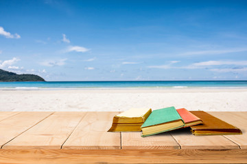 tree aged book and grunge paper on wooden platform beside tropical beach and blue sea on day noon light.