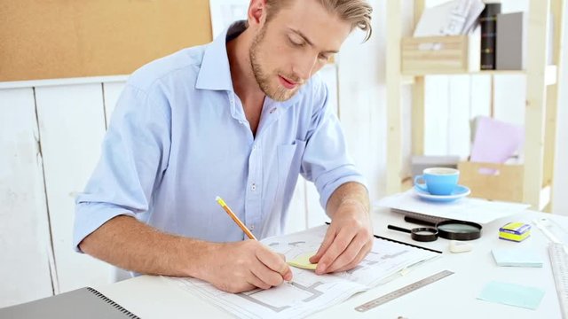 Successful architector working with drawings sitting at workplace Slow motion