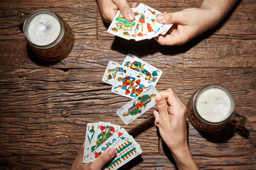 Hände beim Kartenspiel mit Bier