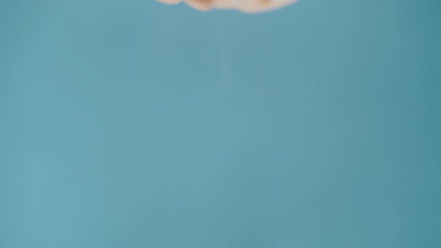 Hand of the cook salts food on a blue background