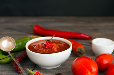 Chili sauce, salsa sauce, tomatoes, dried chili pods, fresh chili pods, green chili pods, wooden table.